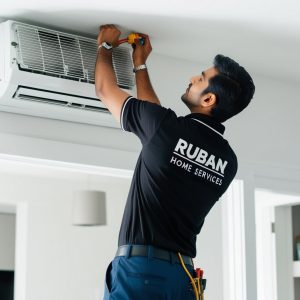 indian AC technician installing split Air conditioner wear black collar t-shirt and Ruban Home Services written on it in white colour indian AC technician installing split Air conditioner wear black collar t-shirt and Ruban Home Services written on it in white colour